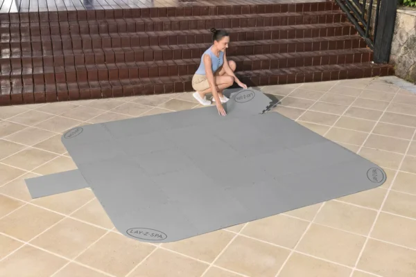 view_of_a_woman_connecting_the_elements_of_a_protective_mat_under_a_jacuzzi_3b3d Podkład pod jacuzzi Bestway Lay-Z-Spa 196 × 196 cm