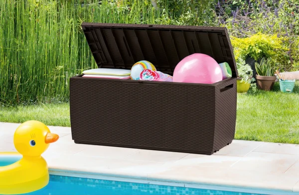 Brązowa skrzynia balkonowa Keter CAPRI RATTAN BOX 305L otwarta z zabawkami plażowymi i kocem Brązowa skrzynia balkonowa Keter CAPRI RATTAN BOX 305L otwarta z zabawkami plażowymi i kocem