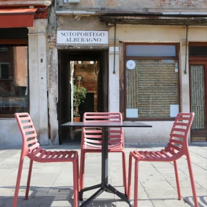 Ujęcie stołu i dwóch krzeseł Nardi DOGA BISTROT Bianco w kolorze różowym na tle kamiennej posadzki Ujęcie stołu i dwóch krzeseł Nardi DOGA BISTROT Bianco w kolorze różowym na tle kamiennej posadzki
