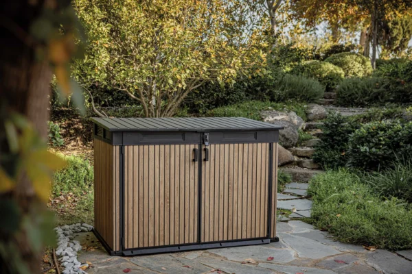 Szafa wielofunkcyjna Deco Horizontal 2020L Venetian Brown Keter w aranżacji ogrodowej na kamiennej ścieżce