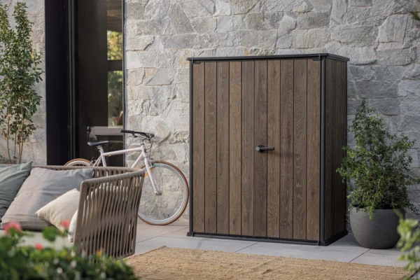 Szafa ogrodowa Keter Deco Vertical 1400L Walnut w aranżacji na tarasie przy kamiennej ścianie