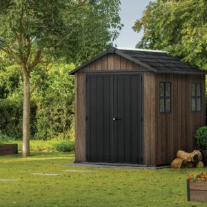 Domek narzędziowy Keter DECO APEX 757/775 w kolorze orzecha włoskiego z czarnymi drzwiami i oknami w ogrodzie Domek narzędziowy Keter DECO APEX 757/775 w kolorze orzecha włoskiego z czarnymi drzwiami i oknami w ogrodzie