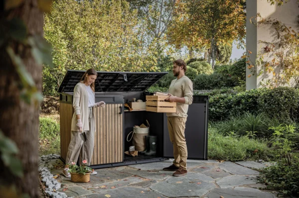 Szafa wielofunkcyjna Deco Horizontal 2020L Venetian Brown Keter z otwartymi drzwiami i klapą w ogrodowej aranżacji z parą osób