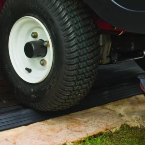 Zbliżenie na koło kosiarki przejeżdżającej przez czarną matę najazdową przy domku DECO APEX 7511/1175 ASHWOOD Zbliżenie na koło kosiarki przejeżdżającej przez czarną matę najazdową przy domku DECO APEX 7511/1175 ASHWOOD